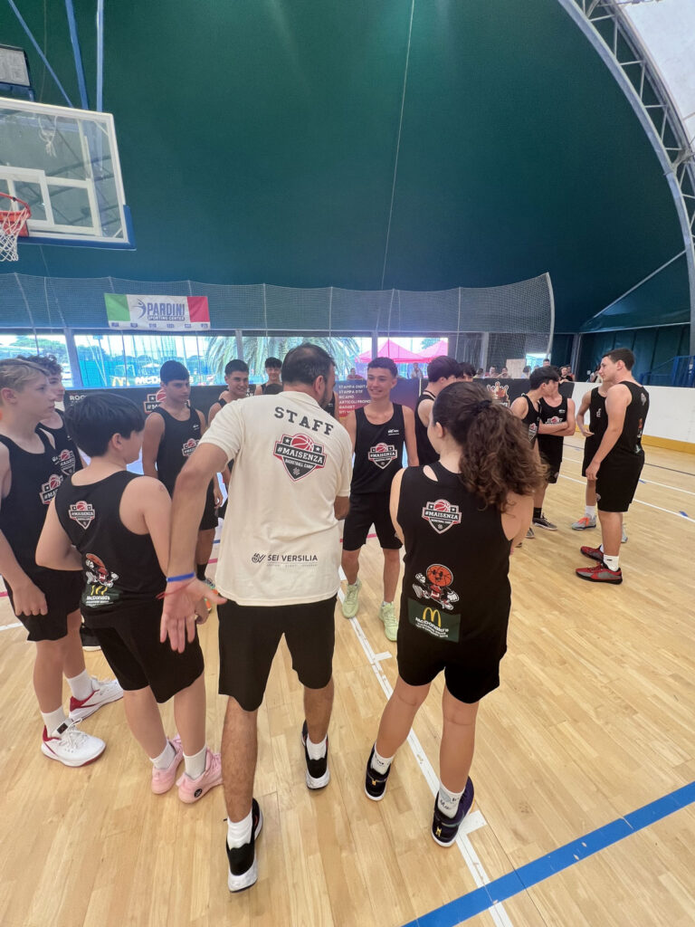 Gruppo di ragazzi ascolta le indicazioni dell'allenatore in palestra