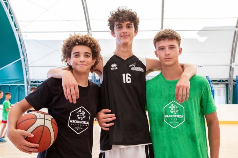 Tre ragazzi del camp in posa abbracciati con il pallone in palestra