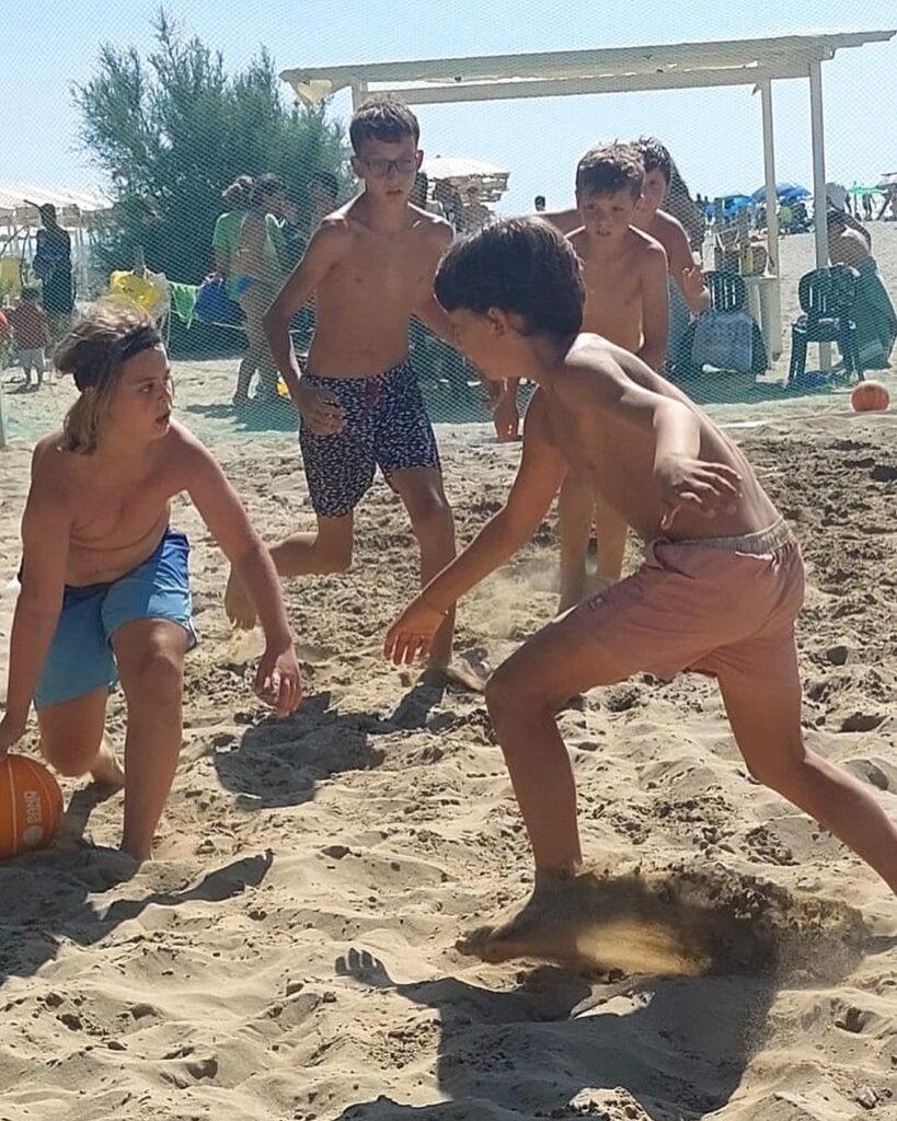 Due ragazzi giocano uno contro uno a basket sulla sabbia in spiaggia