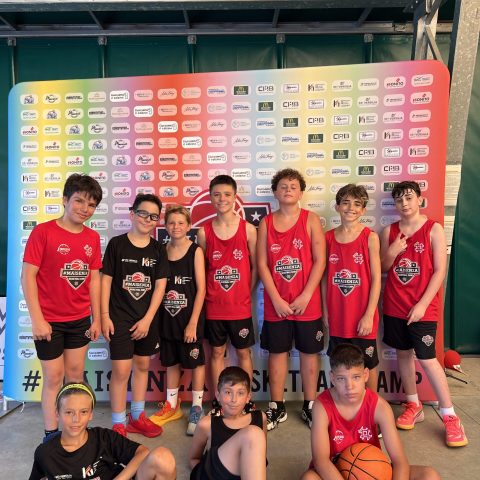 Squadra di ragazzi in canotta rossa e nera del Maisenza Basketball Camp davanti al pannello sponsor