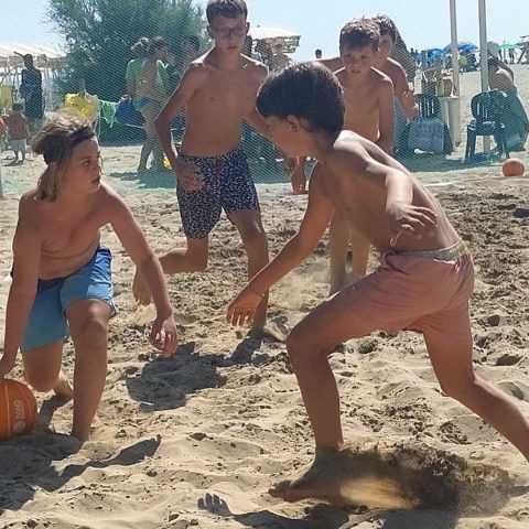 Due ragazzi giocano uno contro uno a basket sulla sabbia in spiaggia