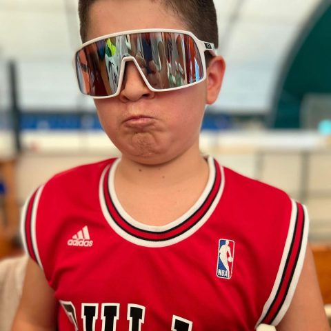 Ragazzo con canotta dei Chicago Bulls e occhiali sportivi a specchio fa una smorfia al camp