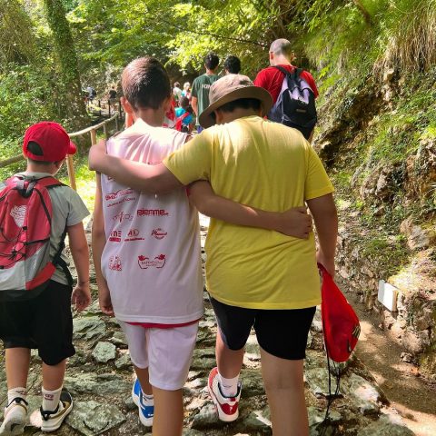 Due ragazzi del camp camminano abbracciati su un sentiero nel bosco durante un'escursione
